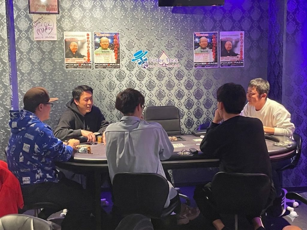 ポーカールームでテーブルを囲み、プレイヤーたちがポーカーを楽しんでいる様子