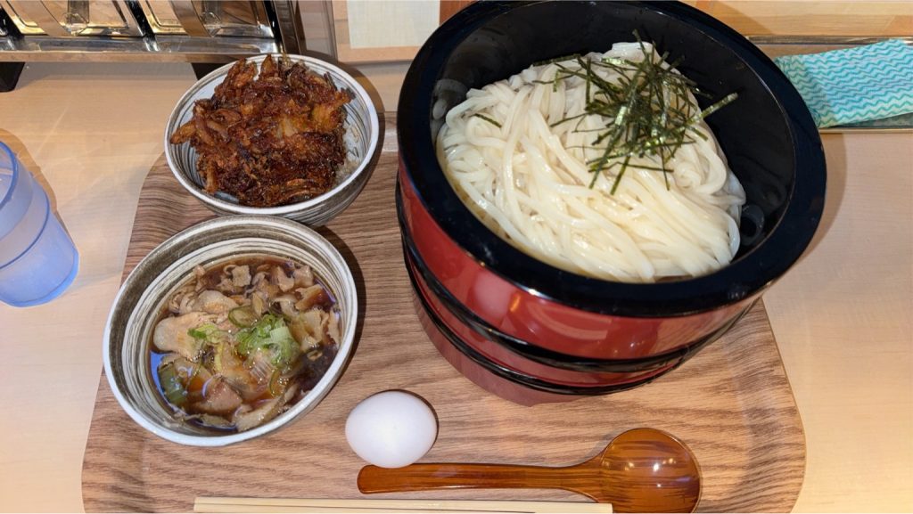 うどん白糸のつけうどんとかき揚げ丼のセット。つけ汁と食べ放題のたまごが添えられたボリュームのあるメニュー。